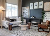 Thumbnail 13 of 16 - A living room with a white sofa, a grey couch, a brown chair, and a grey rug.