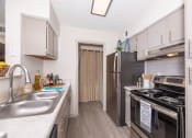 Thumbnail 5 of 31 - Pet-Friendly Apartments in Lawrenceville– Park on Sweetwater – a kitchen with stainless steel appliances and white cabinets