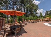 Thumbnail 18 of 31 - Pet-Friendly Apartments in Lawrenceville– Park on Sweetwater – a patio with chairs and umbrellas and a pool