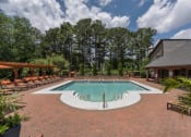 Thumbnail 2 of 31 - Pet-Friendly Apartments in Lawrenceville– Park on Sweetwater – a pool with chairs and a house with trees in the background
