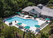 Thumbnail 15 of 35 - Pet-Friendly Apartments in Savannah, GA – The Palms at Chatham – arial view of a resort style pool with lounge chairs and umbrellas
