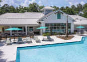 Thumbnail 14 of 35 - Pet-Friendly Apartments in Savannah, GA – The Palms at Chatham – a swimming pool with chaise lounge chairs and umbrellas