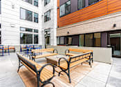 Thumbnail 51 of 54 - A wooden bench sits on a patio in front of a building.