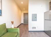 Thumbnail 19 of 54 - A green couch sits in a hallway with a refrigerator on the right.