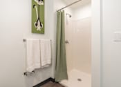 Thumbnail 17 of 54 - A bathroom with a green shower curtain and a white towel hanging on a rack.