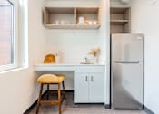 Thumbnail 25 of 54 - A kitchen with a stool, a fridge and a counter.