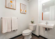 Thumbnail 28 of 54 - A white toilet sits next to a white sink in a bathroom.