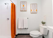 Thumbnail 24 of 54 - A bathroom with a toilet, sink, and orange shower curtain.