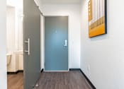 Thumbnail 23 of 54 - A hallway with a blue door and a painting on the wall.