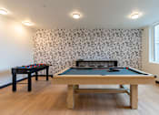 Thumbnail 40 of 54 - A pool table with a black cloth and a foosball table with black and red balls.