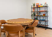 Thumbnail 39 of 54 - A round wooden table surrounded by chairs in a room with a shelf in the background.
