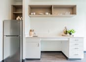 Thumbnail 13 of 54 - A kitchen with a refrigerator, white desk, and drawers.