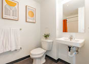 Thumbnail 11 of 54 - A white toilet sits in a bathroom next to a white sink.