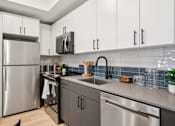Thumbnail 13 of 78 - A modern kitchen with a stainless steel refrigerator and black cabinets.