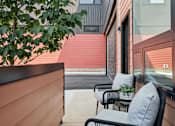 Thumbnail 64 of 78 - A patio with a chair and a table with a plant on it.