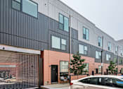 Thumbnail 73 of 78 - A modern building with a black and pink facade and a car parked in front.