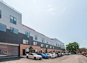 Thumbnail 78 of 78 - A parking lot with cars and a building with a red stripe.