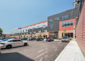 Thumbnail 77 of 78 - A parking lot with cars and a building in the background.