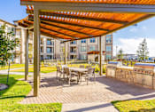 Thumbnail 17 of 29 - A patio with a table and chairs under a pergola.
