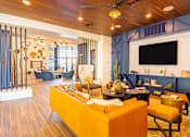 Thumbnail 26 of 29 - A living room with a yellow couch and a television on the wall.