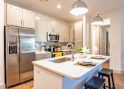 Thumbnail 1 of 29 - A modern kitchen with a stainless steel refrigerator and a white island.