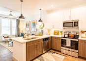 Thumbnail 4 of 29 - A modern kitchen with wooden cabinets and stainless steel appliances.