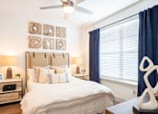 Thumbnail 8 of 29 - A bedroom with a large bed, a ceiling fan, and a nightstand with a lamp.
