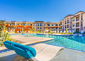 Thumbnail 15 of 29 - A poolside lounge chair overlooks a swimming pool at a resort.