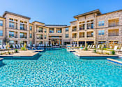 Thumbnail 13 of 29 - A large swimming pool in front of a multi-story residential building.