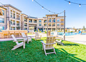 Thumbnail 20 of 29 - A sunny day at a poolside with lawn chairs and a building in the background.