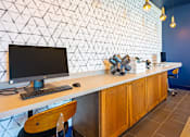 Thumbnail 28 of 29 - A white desk with a black monitor and keyboard sits against a wall with a geometric pattern.