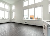 Thumbnail 33 of 40 - A large empty room with a kitchen area to the right.