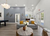 Thumbnail 14 of 15 - Kissimmee, FL Townhomes for Rent - Estates at Lake Cecile – A modern clubhouse with a grey couch and a coffee table.