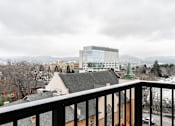 Thumbnail 15 of 40 - A balcony overlooks a cityscape with a large building in the distance.