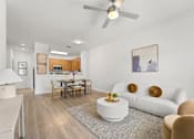 Thumbnail 4 of 15 - Three- & Four-Bedroom Townhomes in Kissimmee, FL - Estates at Lake Cecile – A living room with a white couch and a wooden dining table.