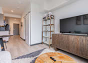 Thumbnail 7 of 40 - A modern living room with a wooden entertainment center and a flat screen TV.