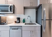 Thumbnail 1 of 40 - A modern kitchen with a stainless steel refrigerator and white cabinets.