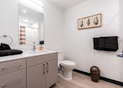 Thumbnail 12 of 40 - A bathroom with a toilet, sink, and a mirror.