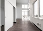 Thumbnail 28 of 40 - A long hallway with white walls and wood floors.