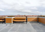 Thumbnail 35 of 40 - A wooden bench sits on a patio with a view of the horizon.