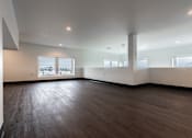 Thumbnail 19 of 40 - A large empty room with wooden floors and white walls.