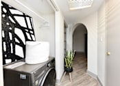 Thumbnail 6 of 51 - A laundry basket sits on a washing machine in a small room.
