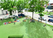 Thumbnail 41 of 51 - A playground with a green surface and children playing.