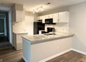Thumbnail 1 of 25 - A kitchen with a granite countertop and black appliances.