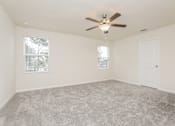 Thumbnail 22 of 38 - A room with a ceiling fan and carpeted floor.