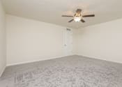 Thumbnail 20 of 38 - A room with a ceiling fan and carpeted floor.
