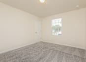Thumbnail 19 of 38 - A room with a carpeted floor and a window with blinds.