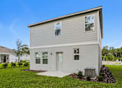 Thumbnail 2 of 38 - A two-story house with a grey exterior and a white door.