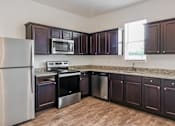 Thumbnail 61 of 75 - A kitchen with dark brown cabinets and a stainless steel refrigerator.