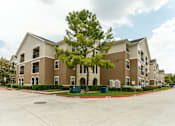 Thumbnail 12 of 13 - A large apartment complex with a tree in front.